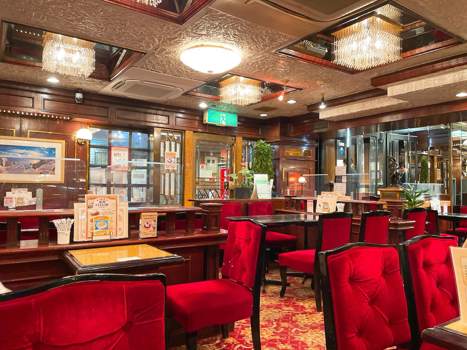 池袋の静かな喫茶店でコーヒーカップと開いた本が置かれたテーブル、窓際の自然光が差し込む落ち着いた雰囲気